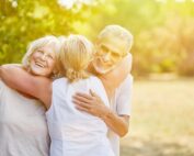 Senior couple hugging their insurance agent outdoors, smiling with peace of mind