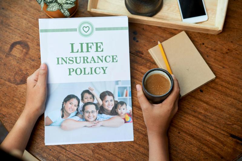 Hands holding a life insurance policy with a family photo on the cover