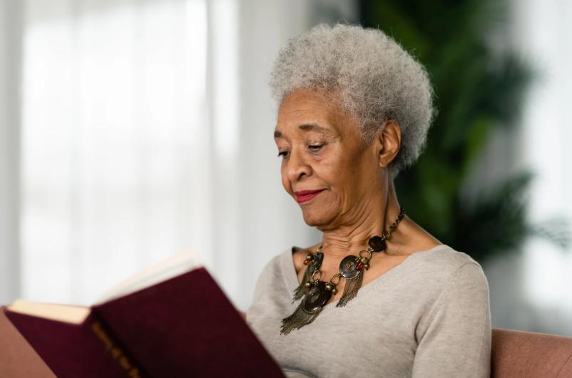Elderly woman reading a book, planning her final expense arrangements