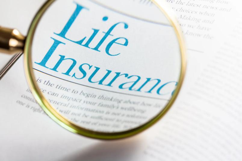 Magnifying glass highlighting the words life insurance on a white page