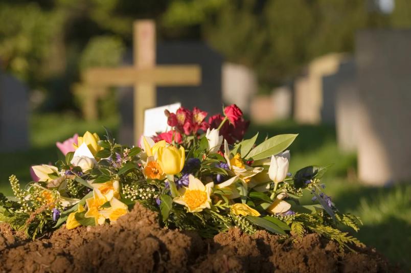 Fresh flowers on a newly covered grave in a cemetery