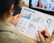 Insurance agent holding a business plan with graphs and charts during a video meeting