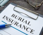 Close-up of burial insurance policy on clipboard with pen and glasses