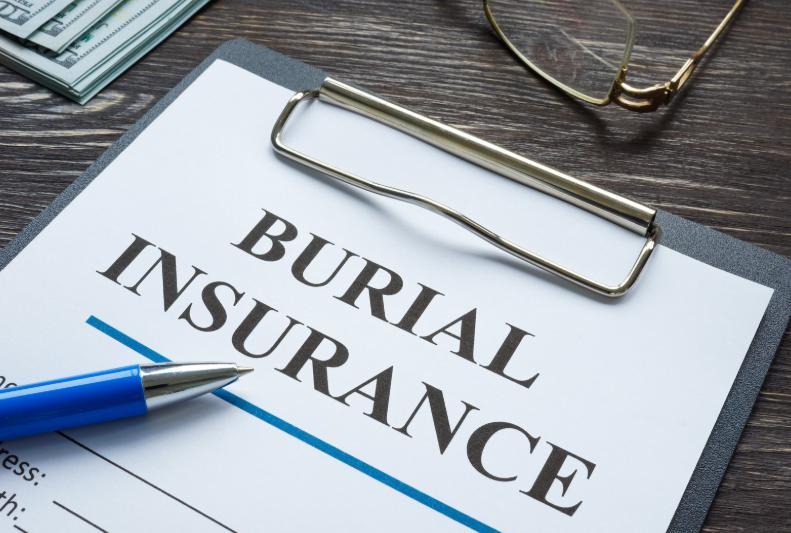 Close-up of burial insurance policy on clipboard with pen and glasses