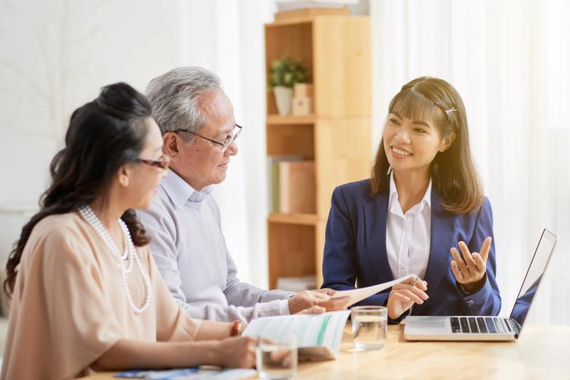 Financial advisor explaining life insurance options to a senior couple at a desk