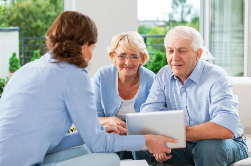 Life insurance agent showing policy options to smiling senior couple