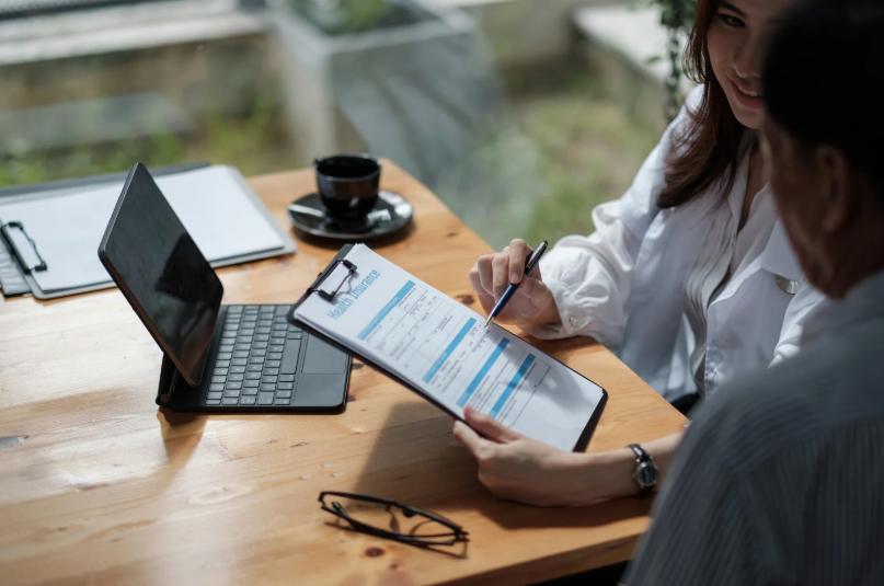 Insurance advisor explaining a final expense policy to a client with a clipboard