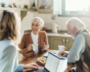 Senior couple consulting with a professional insurance agent at their kitchen table