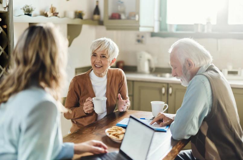 Senior couple consulting with a professional insurance agent at their kitchen table