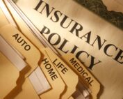 Insurance policy paperwork with labeled folders for auto, life, medical, and home coverage