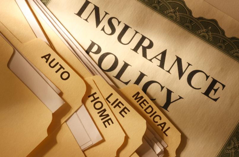 Insurance policy paperwork with labeled folders for auto, life, medical, and home coverage