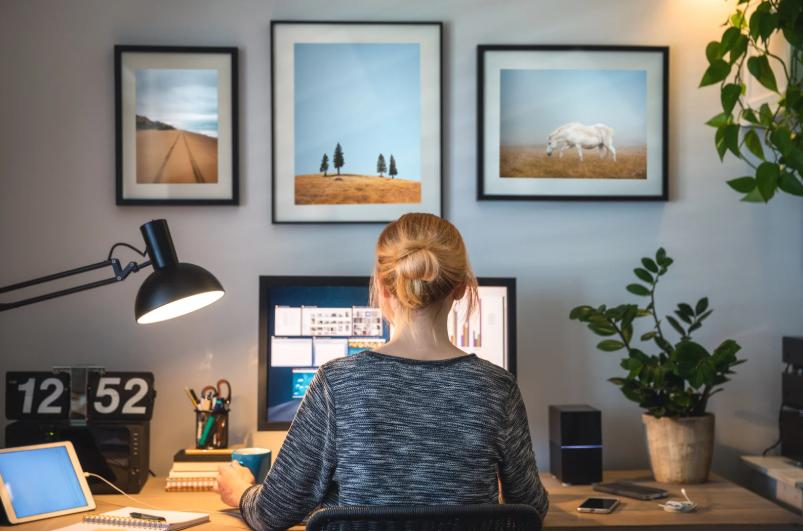 Woman working remotely on a dual-screen home office setup with modern decor