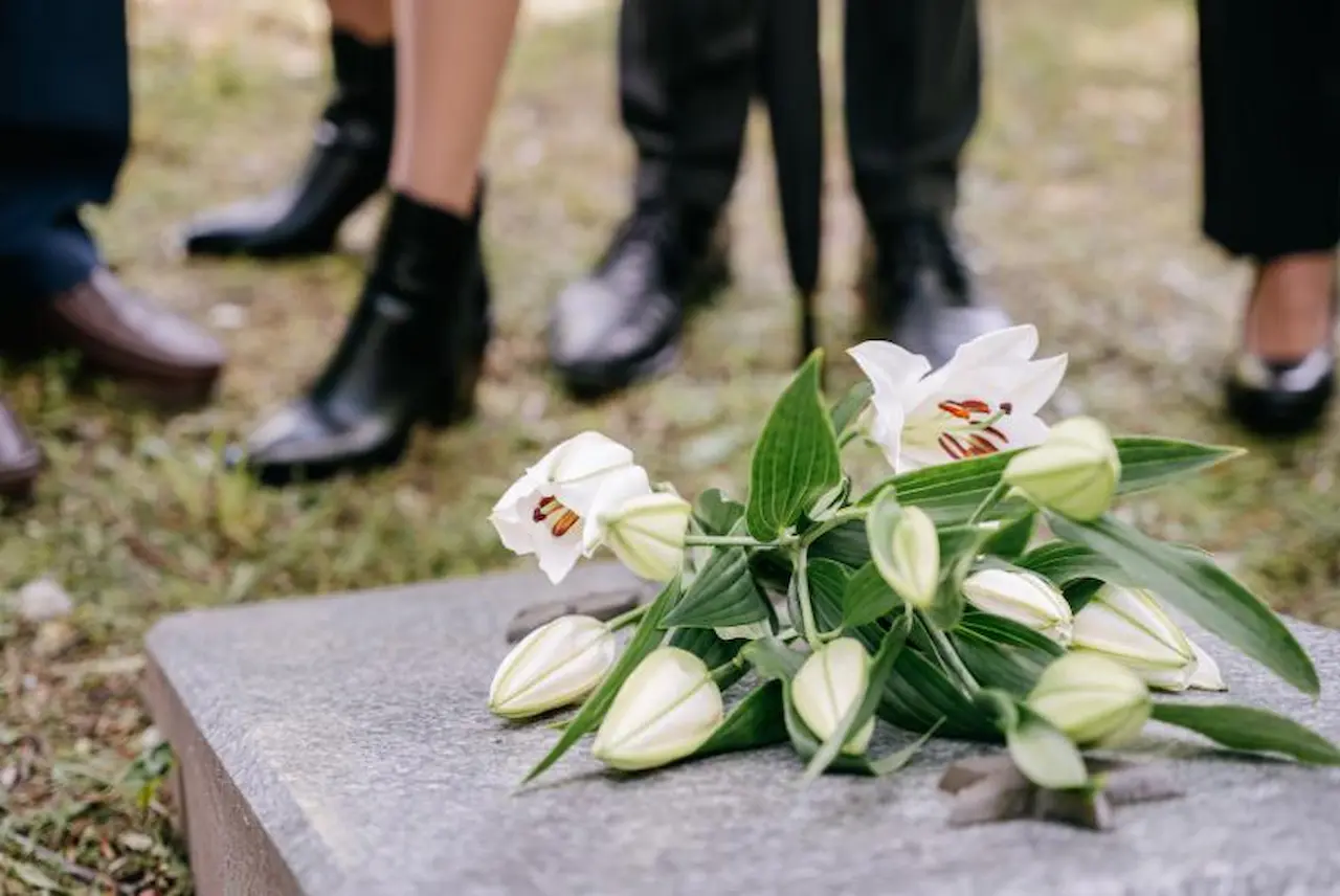 Paying for Funeral Expenses with Life Insurance Funeral flowers on gravestone with people standing in background