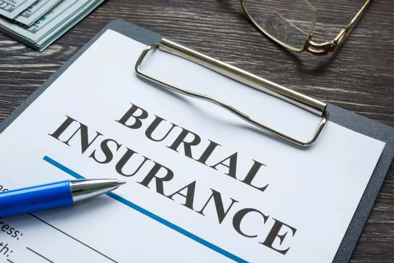 Close-up of burial insurance policy on clipboard with pen and glasses