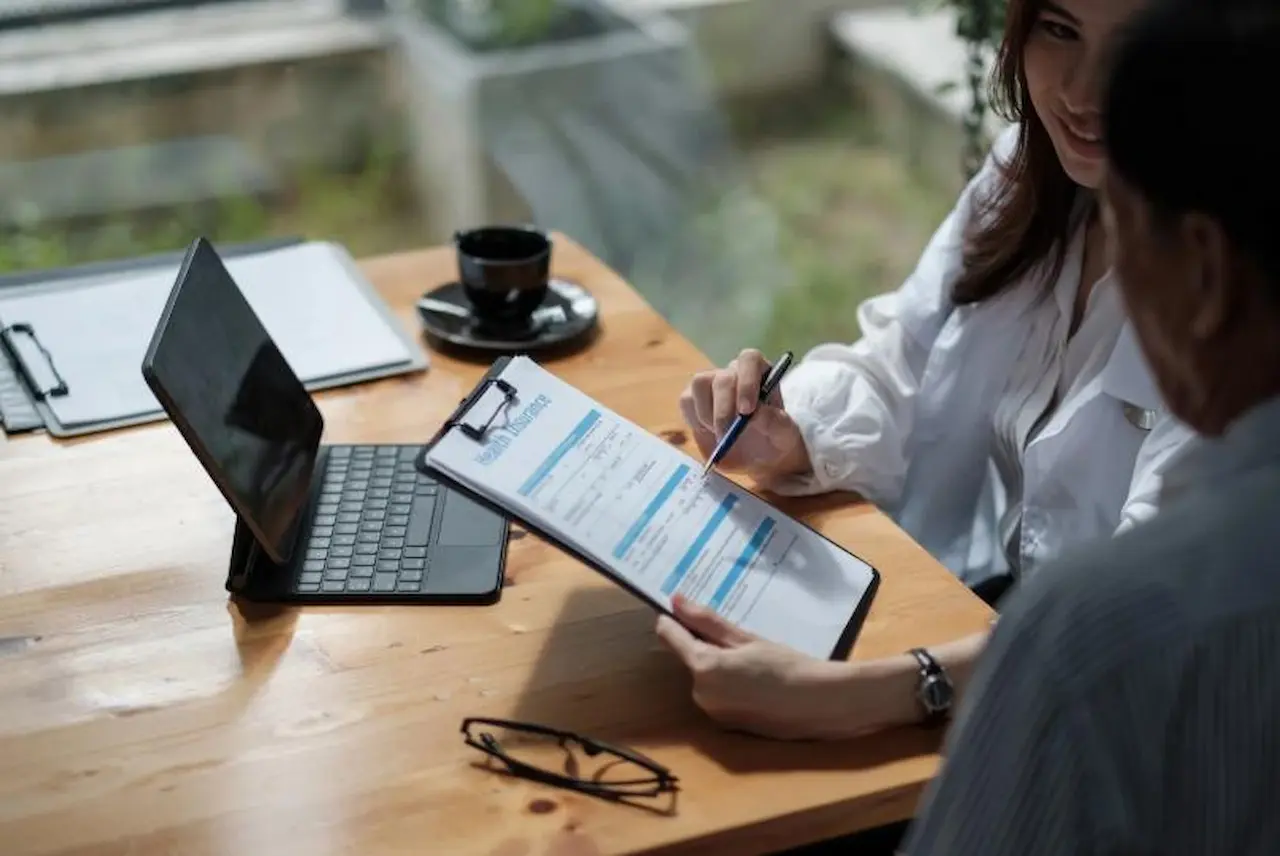 Final Expense Sales Process Insurance advisor explaining a final expense policy to a client with a clipboard
